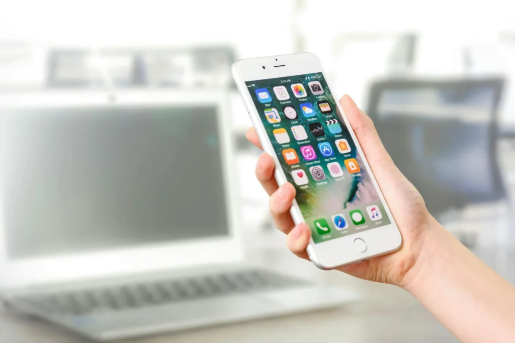 a hand holding a smart phone with app icons on the screen