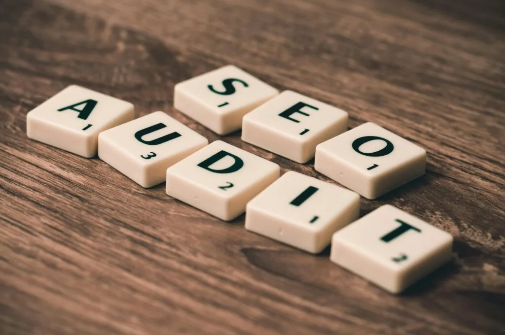 Scrabble tiles spelling 'SEO Audit' on wooden surface, representing website analysis and optimization for small businesses.